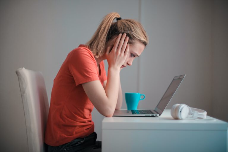 Imagen de una joven experimentando síndrome posvacacional mientras trabaja en su ordenador