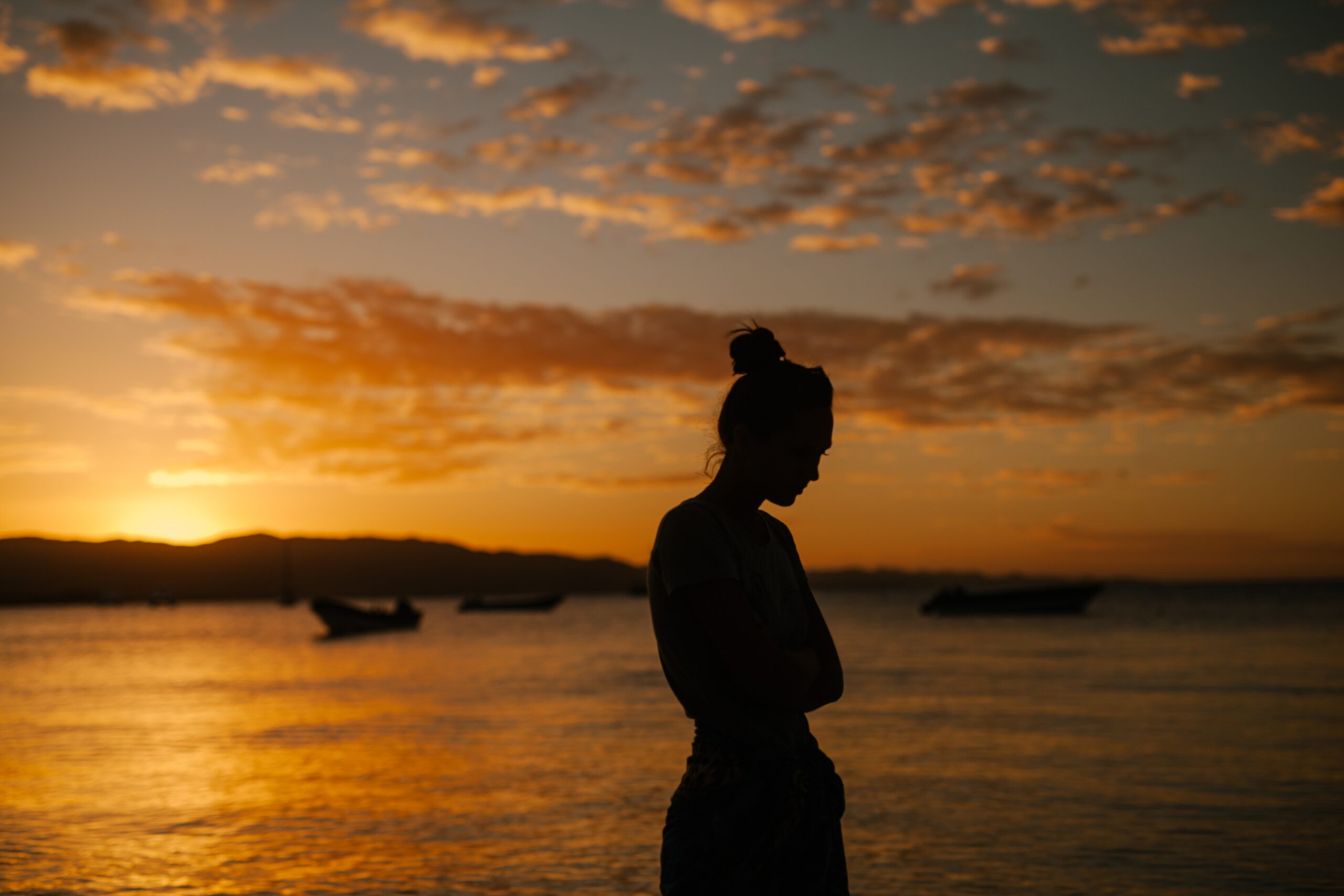 Silueta de una chica practicando mindfulness en un atardecer anaranjado junto al mar