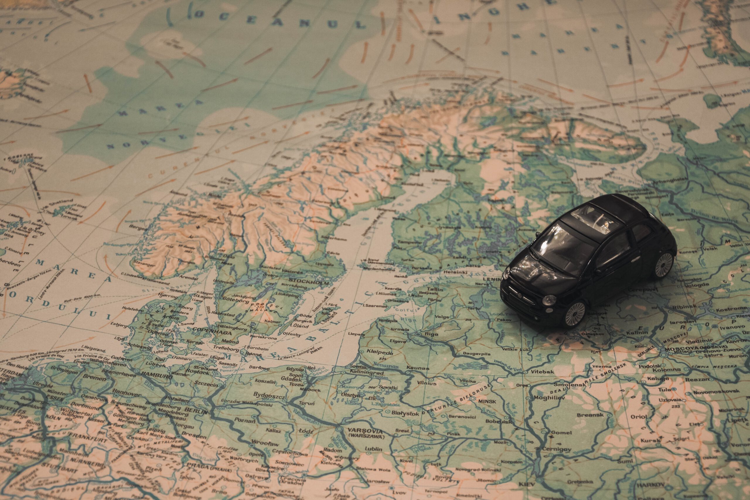 Representación de las vacaciones y el síndrome posvacacional con un coche de juguete sobre el atlas de Europa del Norte