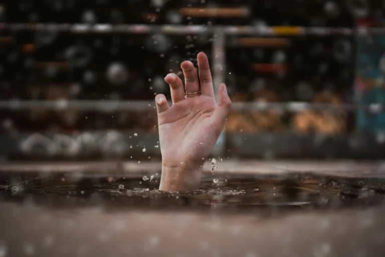 Mano emergiendo del agua con gotas en el aire, representando la sensación de ahogo y desesperación vinculada al miedo al fracaso.