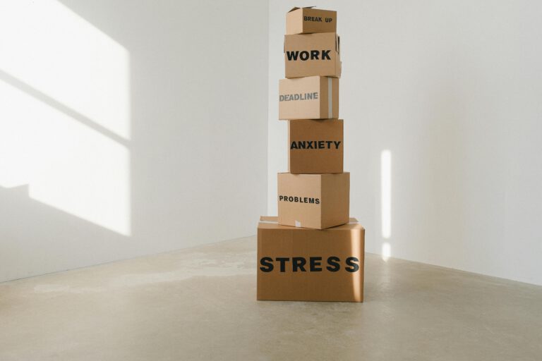 Torre de cajas con palabras como "estrés", "problemas" y "ansiedad", simbolizando la acumulación emocional.